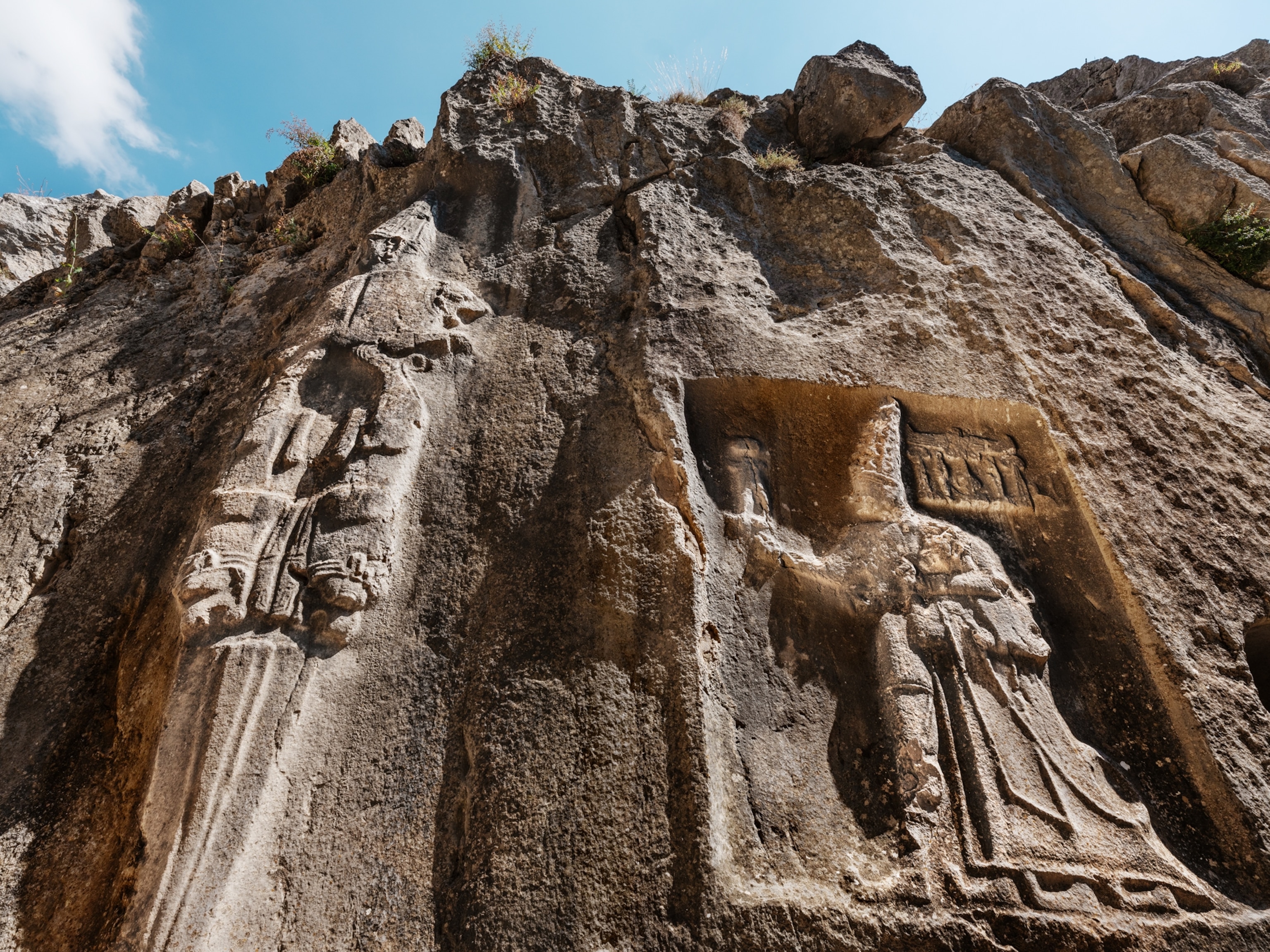 A close-up image shows a depiction of a god and a king carved in stone.
