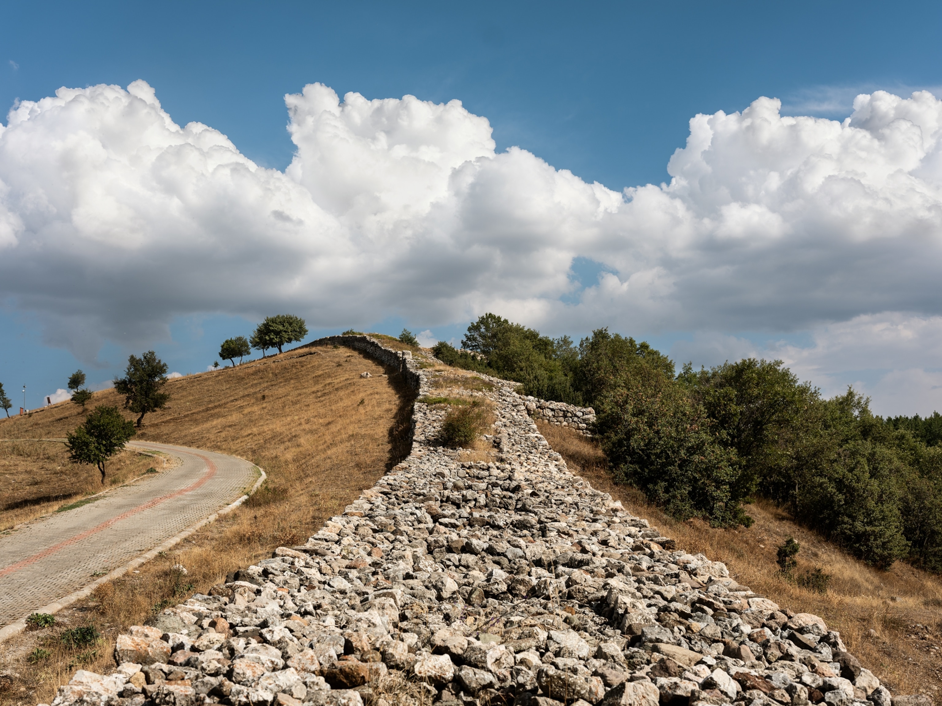 A mudbrick wall lines a hill.