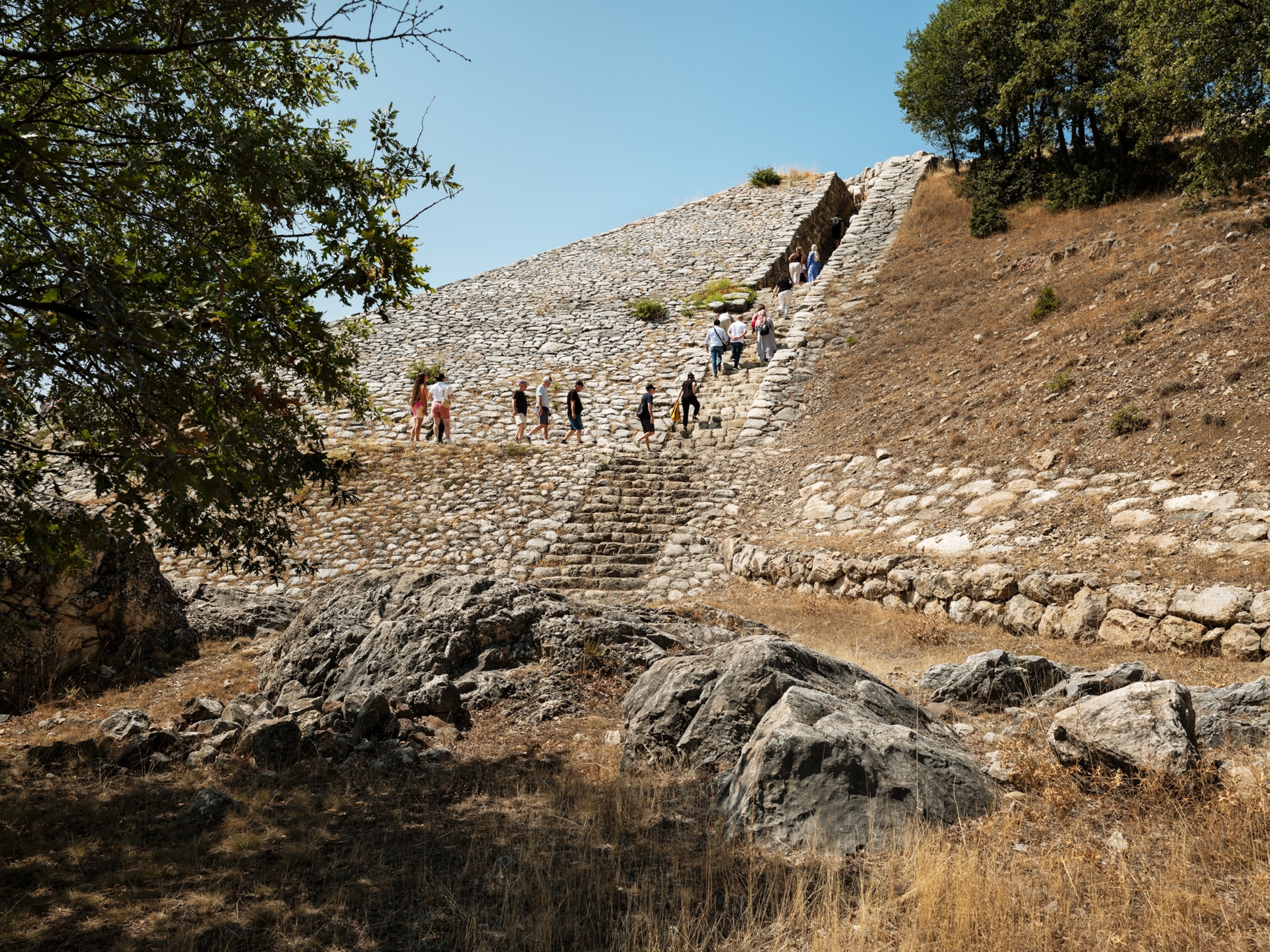A line of tourists walk up stone steps.